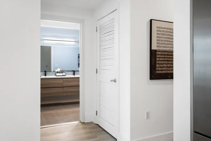 Hall featuring light wood-style flooring and baseboards Closet is Miele washer and dryer units (2023).