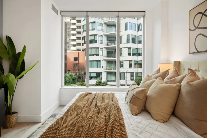 Bedroom with wood updated reengineered floors and baseboards. Floor to ceiling windows.