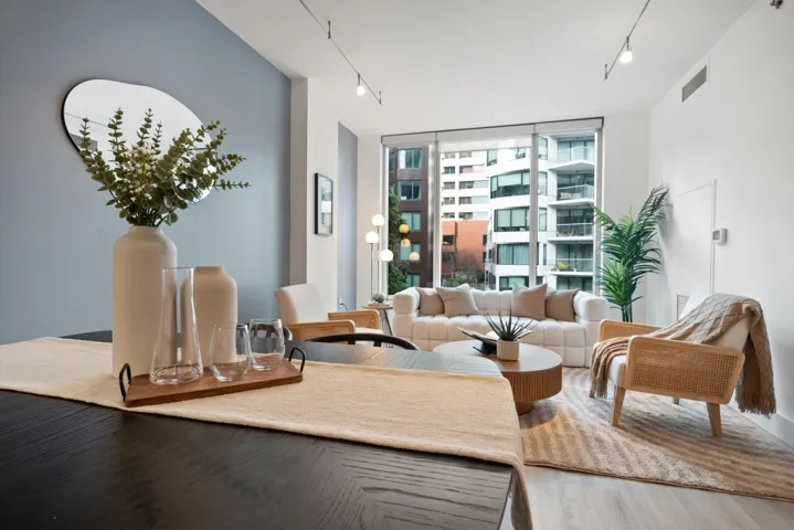 Living area with rail lighting, a wall of windows, and wood finished floors