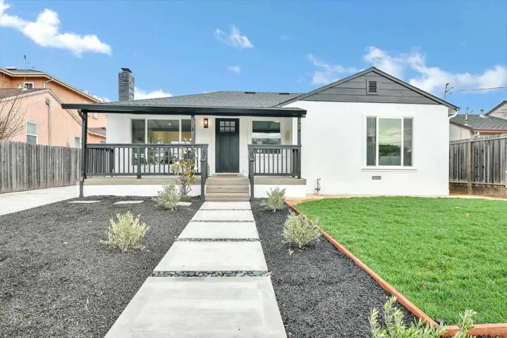 View of front of property featuring a porch, a chimney, stucco siding, and roof with shingles
