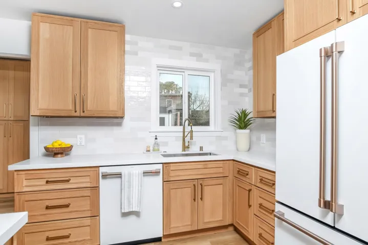 Kitchen featuring white appliances, light brown cabinetry, decorative backsplash, recessed lighting, and light wood-style flooring