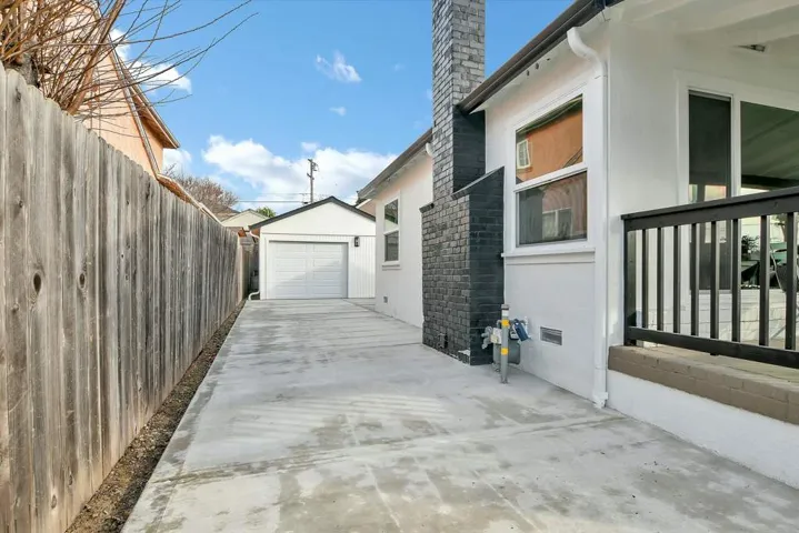 View of property exterior with an outbuilding, driveway, a chimney, stucco siding, and a garage