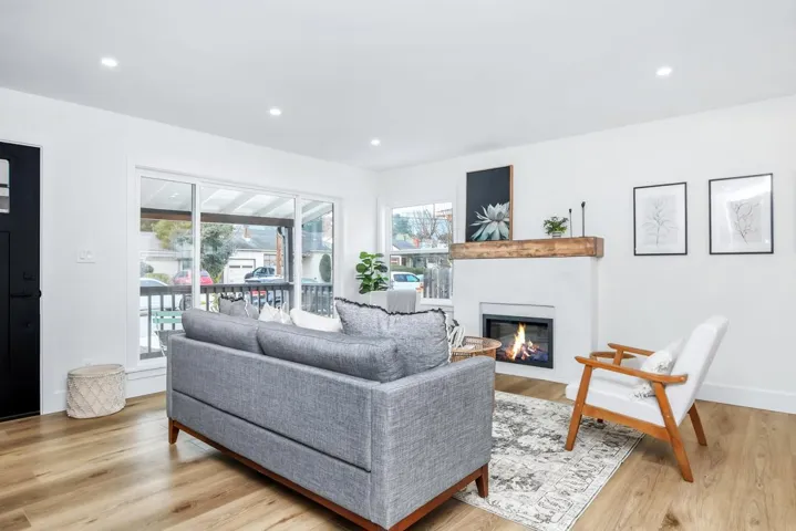 Living area with a glass covered fireplace, light wood-type flooring, and recessed lighting