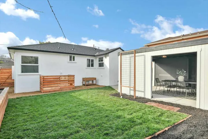Back of house with stucco siding, a shingled roof, and a patio area