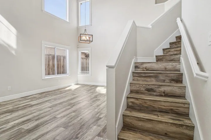 Stairway featuring healthy amount of natural light, wood finished floors, a high ceiling, and a chandelier