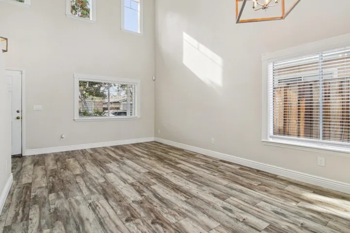 Unfurnished living room featuring wood finished floors and a towering ceiling