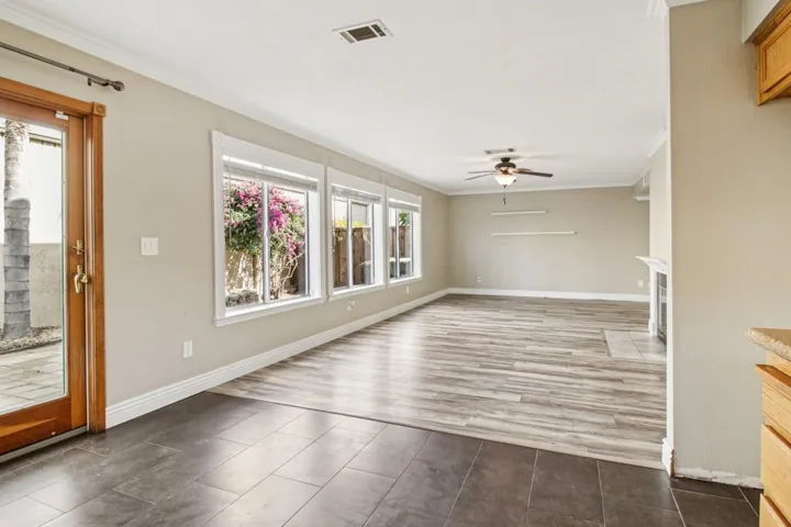 Unfurnished living room with ornamental molding, ceiling fan, a fireplace with flush hearth, and dark wood finished floors