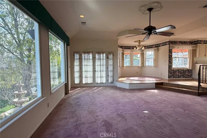 View from side of fireplace in the step-down family room with view of outdoor fountain, and steps leading to the kitchen.