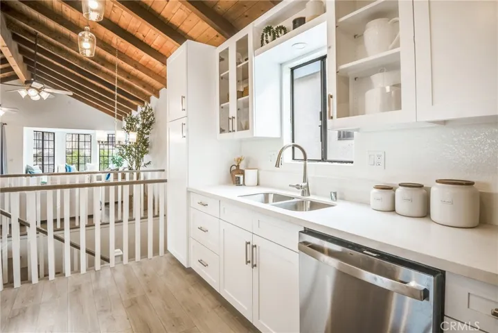 Open kitchen with new shaker cabinetry, quartz counters, stainless appliances including new dishwasher, stove and microwave, pendant lighting, and breakfast bar