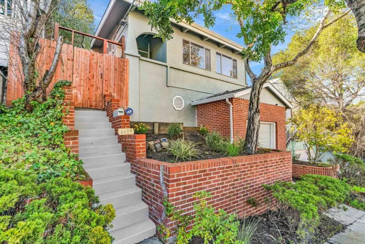 View of front of house with stairs, stucco siding, and brick siding