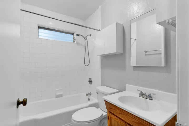 Full bathroom featuring shower / bathtub combination, vanity, and a textured wall