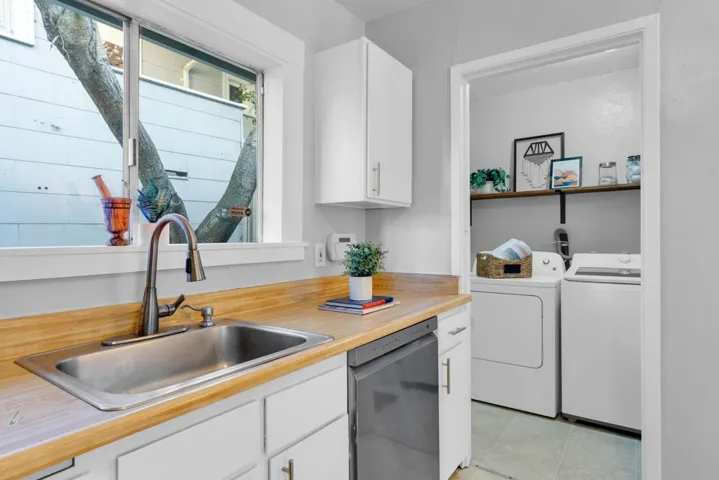 Kitchen with white cabinetry, independent washer and dryer, dishwasher, and light tile patterned floors