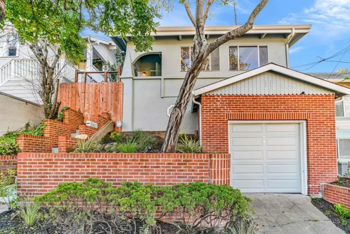 View of front facade with stairway, stucco siding, brick siding, driveway, and a garage