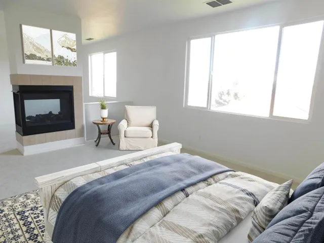 Bedroom with a fireplace and carpet flooring  (Virtual Stage)