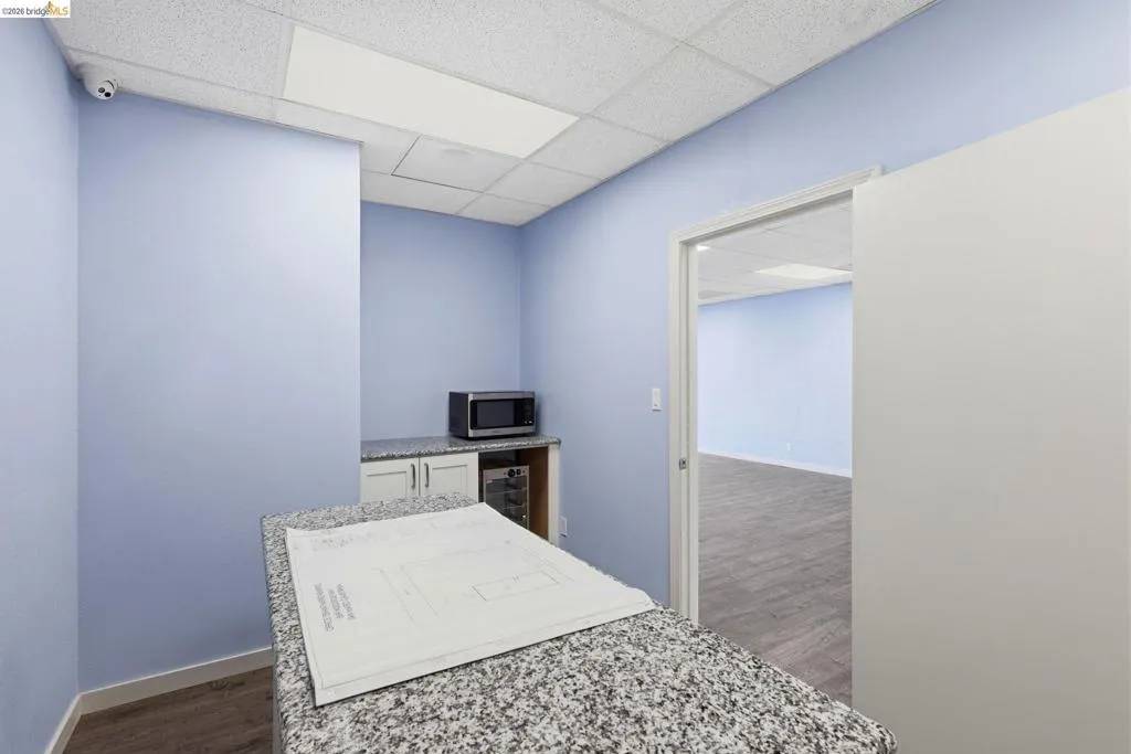 Unfurnished bedroom featuring dark wood-style floors, a paneled ceiling, and wine cooler