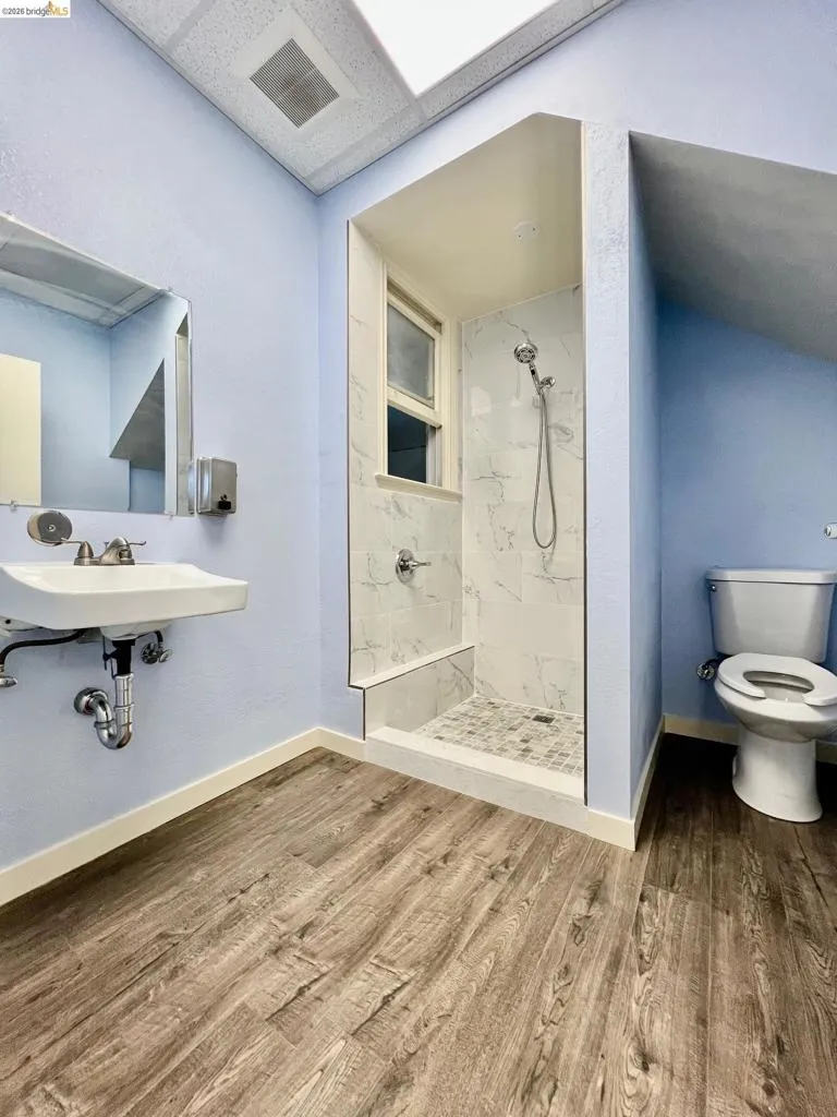 Full bathroom with a marble finish shower and wood finished floors