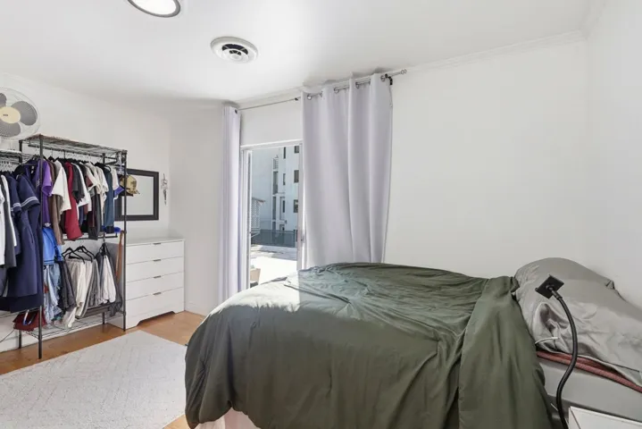 Bedroom featuring wood finished floors, ornamental molding, and connected bathroom