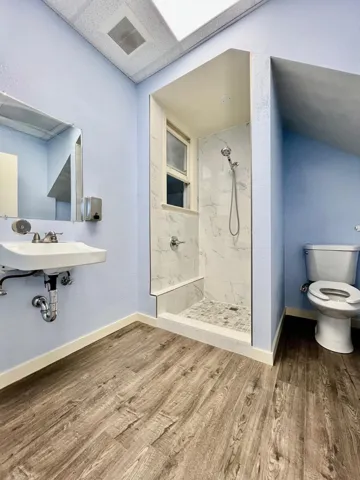 Full bathroom with a marble finish shower and wood finished floors