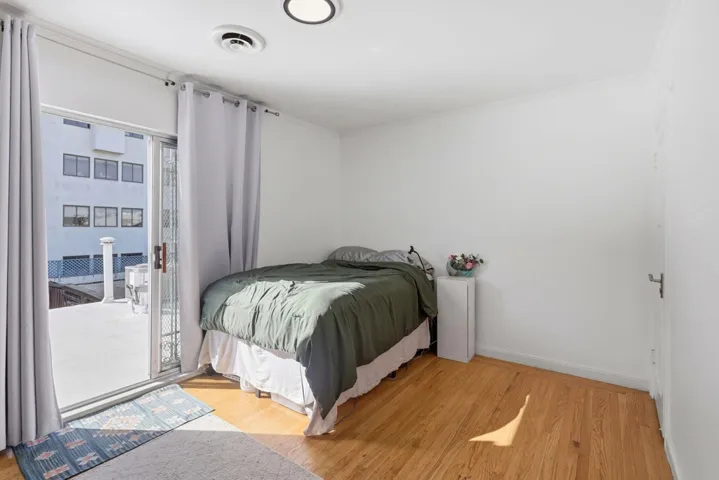 Bedroom featuring light wood finished floors, access to exterior, and ornamental molding