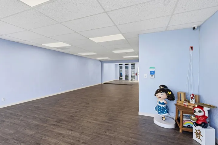 Unfurnished room featuring dark wood-style flooring and a drop ceiling