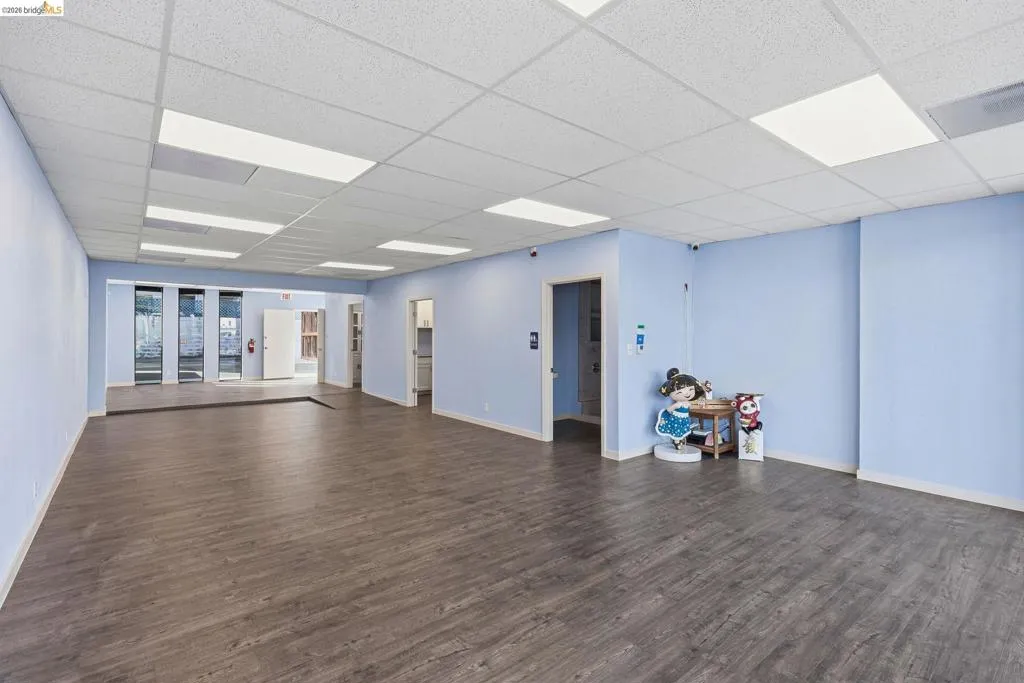 Unfurnished room featuring dark wood-style flooring and a paneled ceiling