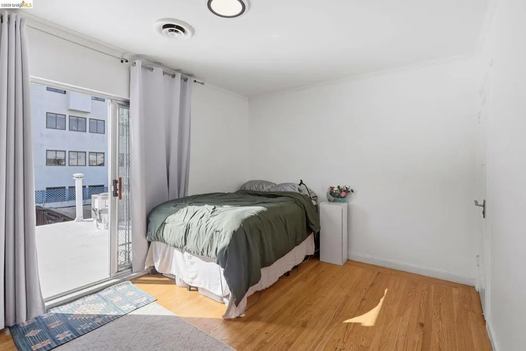 Bedroom featuring light wood finished floors, access to exterior, and ornamental molding