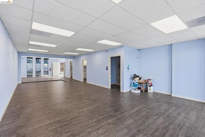 Unfurnished room featuring dark wood-style flooring and a paneled ceiling
