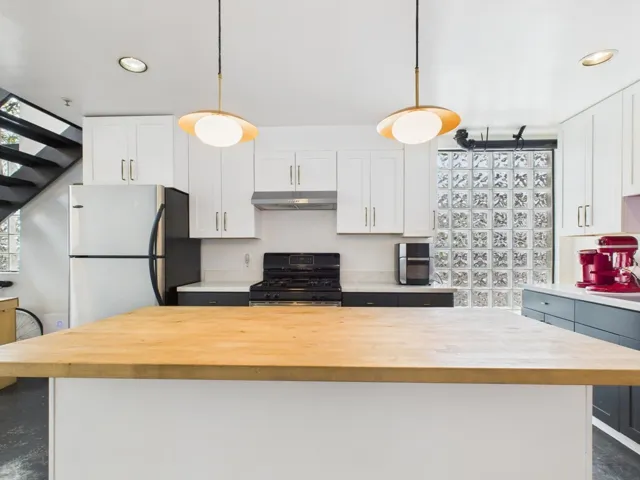 Kitchen with butcher block counters, white cabinetry, freestanding refrigerator, and recessed lighting
