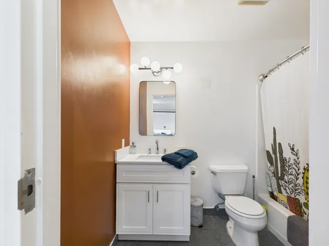 Full bathroom with vanity, shower / bath combo with shower curtain, and dark tile patterned floors