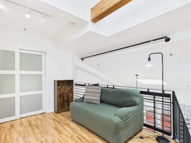 Living area with track lighting, wood finished floors, and an upstairs landing