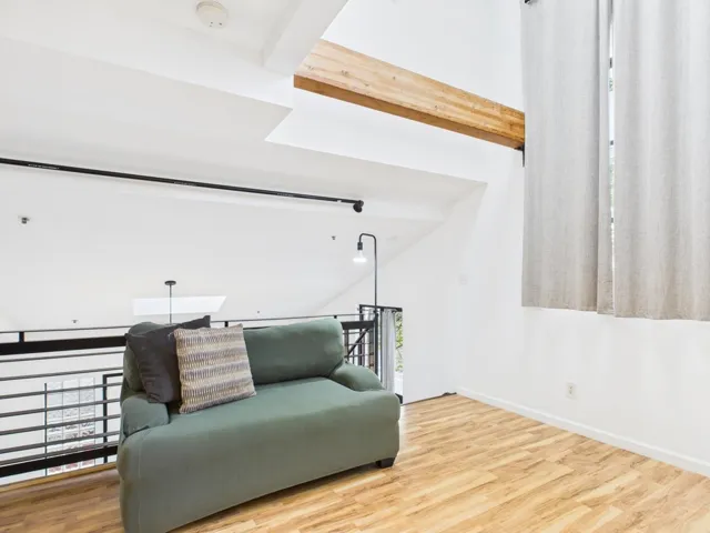 Sitting room with wood finished floors, an upstairs landing, and beamed ceiling