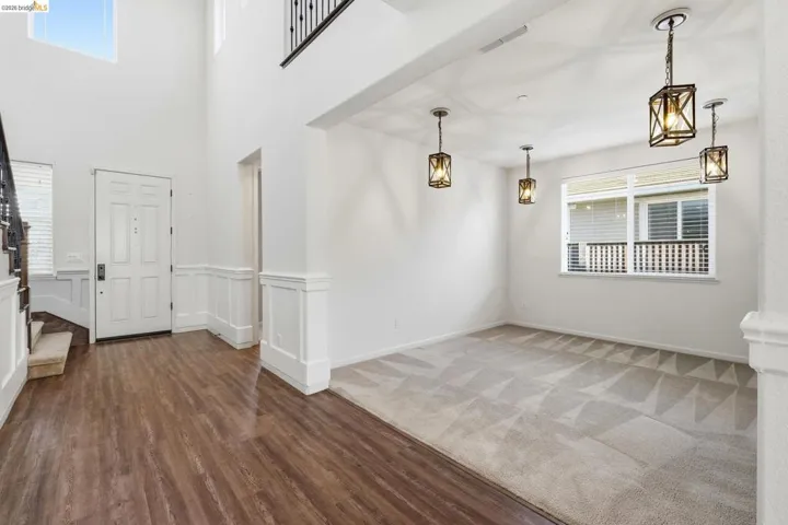 Empty room with healthy amount of natural light, wainscoting, dark wood-type flooring, and a decorative wall