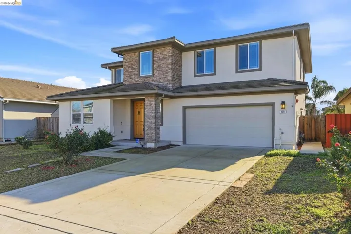 View of front facade with stone siding, stucco siding, concrete driveway, and an attached garage