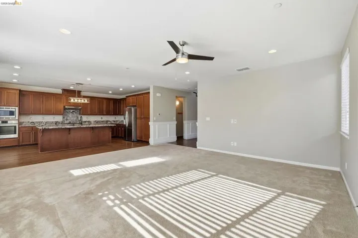 Unfurnished living room with dark colored carpet, recessed lighting, ceiling fan, and a wainscoted wall