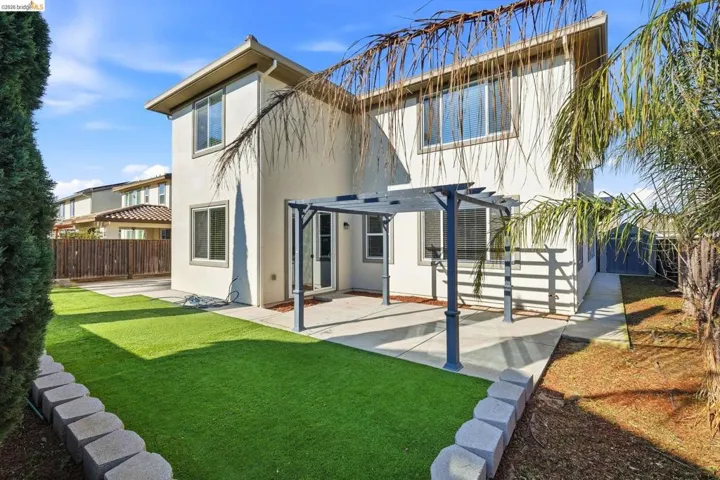 Back of property featuring a fenced backyard, stucco siding, a patio, and a pergola