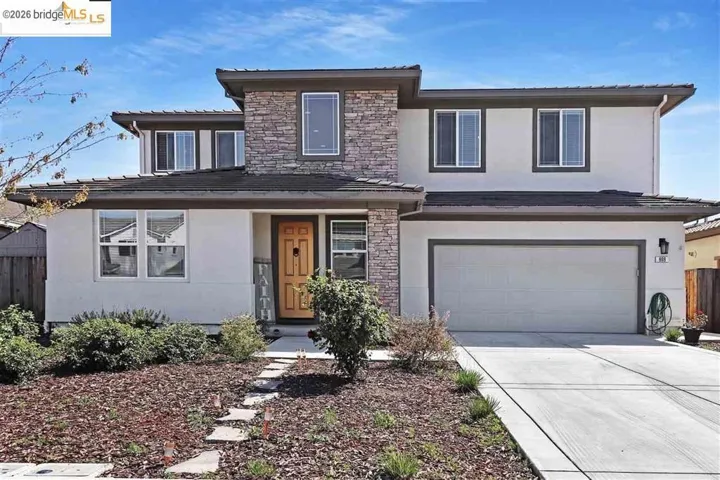 View of front of property featuring stone siding, stucco siding, driveway, and a garage