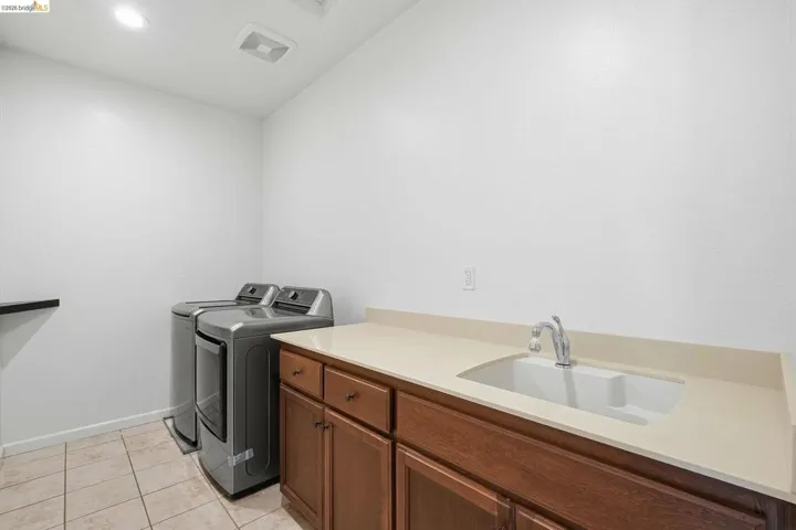 Laundry area featuring washing machine and dryer, light tile patterned floors, cabinet space, and recessed lighting