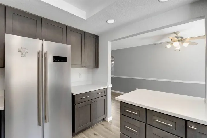 Kitchen with high quality fridge, a textured ceiling, a ceiling fan, light wood-style floors, and dark brown cabinets