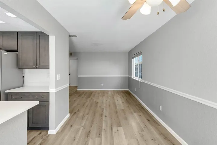Kitchen featuring freestanding refrigerator, light wood-style floors, dark brown cabinets, and ceiling fan