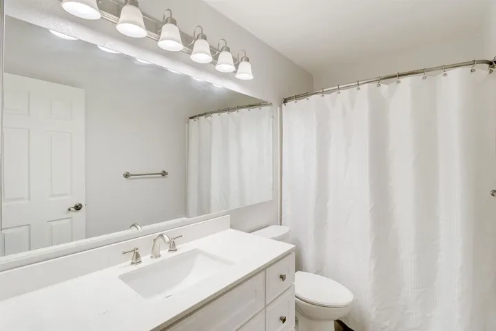 Full bath with curtained shower and vanity