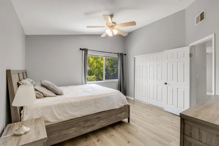 Bedroom with vaulted ceiling, light wood finished floors, a ceiling fan, and a closet