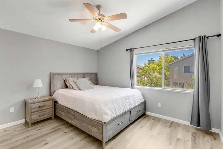 Bedroom with vaulted ceiling, light wood finished floors, and ceiling fan
