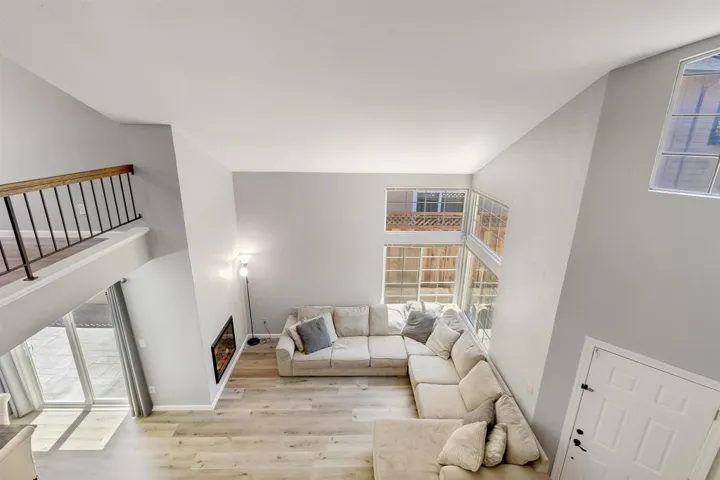Living room featuring plenty of natural light, light wood-style flooring, and a high ceiling