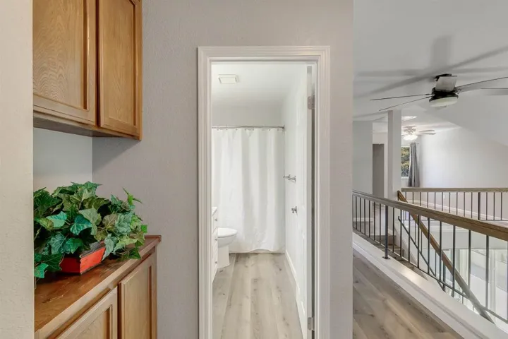 Bathroom with a shower with curtain, light wood finished floors, a textured wall, a ceiling fan, and vanity