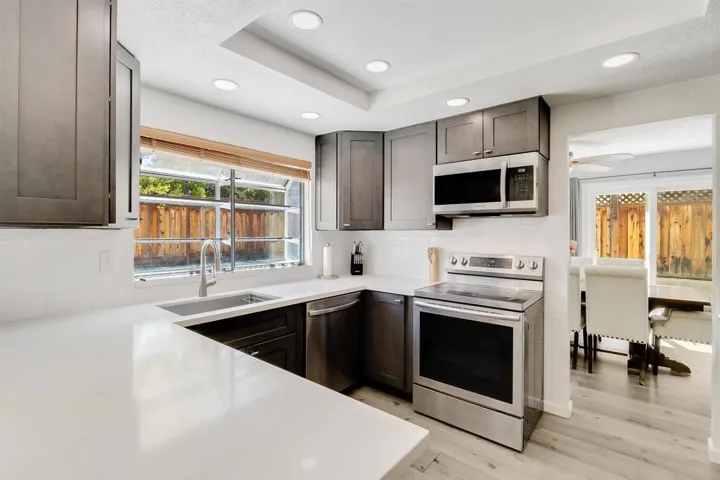 Kitchen featuring stainless steel appliances, light wood-type flooring, backsplash, dark brown cabinetry, and recessed lighting