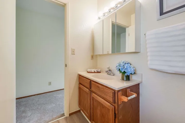 Bathroom featuring vanity, a textured wall, and light wood finished floors