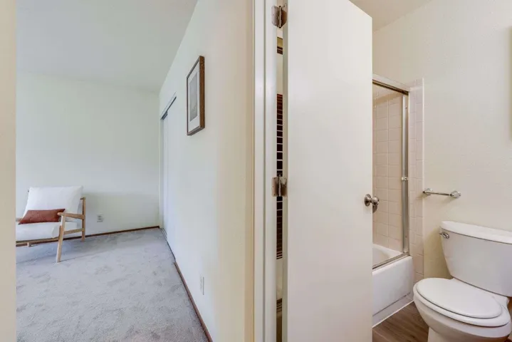 Bathroom featuring bath / shower combo with glass door and light colored carpet