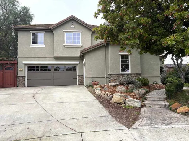 Traditional-style home featuring stone siding, stucco siding, and concrete driveway