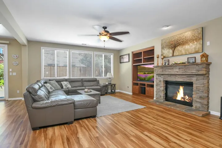 Living area with wood finished floors, a fireplace, and a ceiling fan
