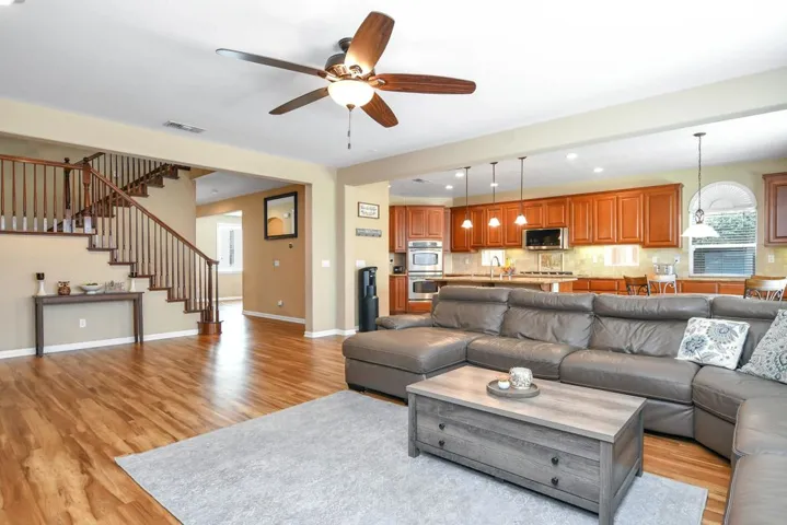 Living area with recessed lighting, light wood-type flooring, a ceiling fan, and stairs